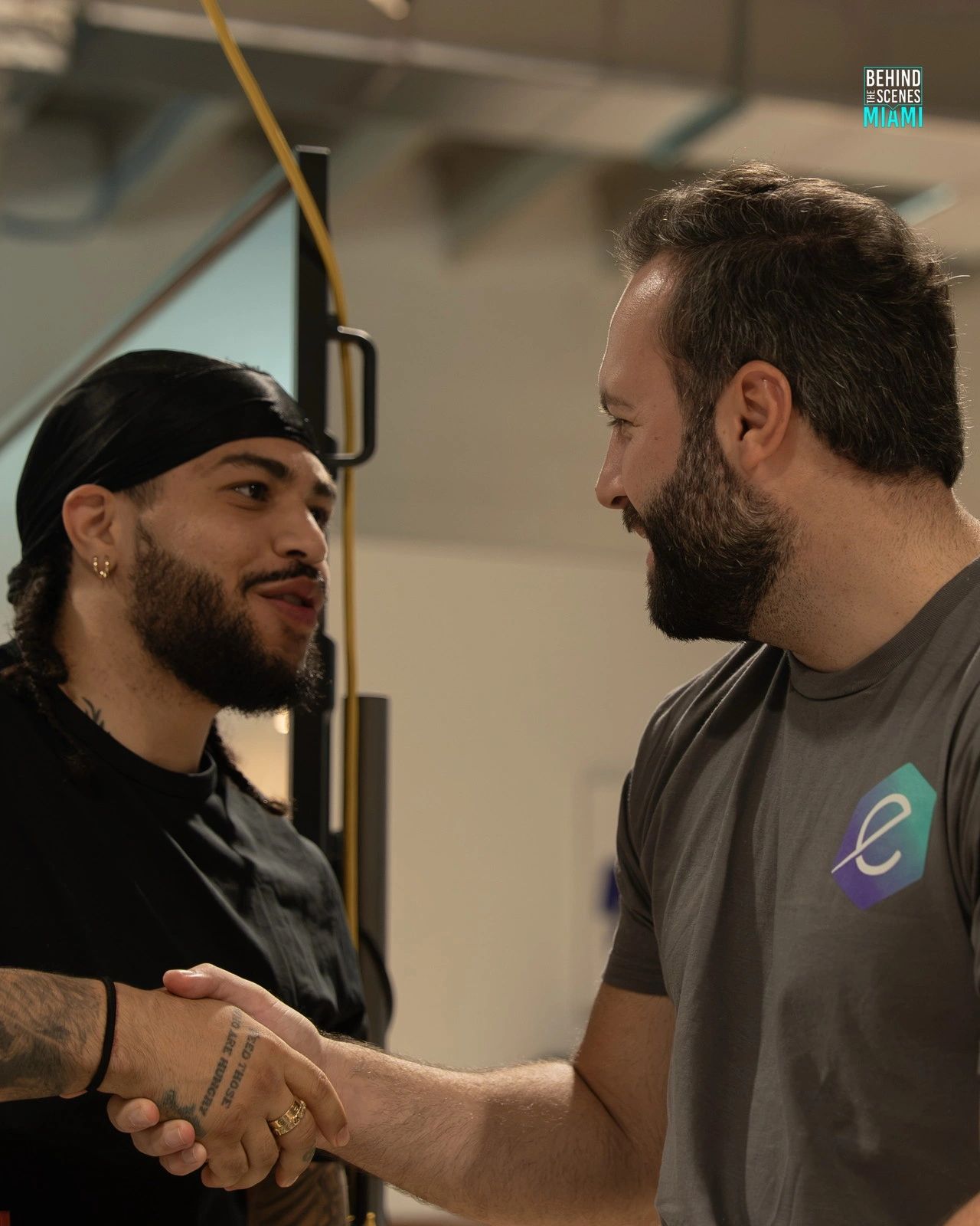Un apretón de manos lo sella: dos builders se conocen en el hackathon del Miami AI Summit.